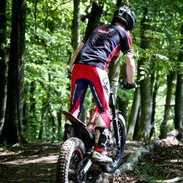a man riding a bike down a dirt road in a forest