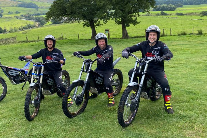 a group of people standing around a motorcycle in a field