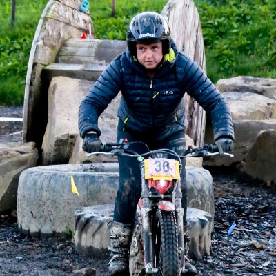a man riding a motorcycle down a dirt road