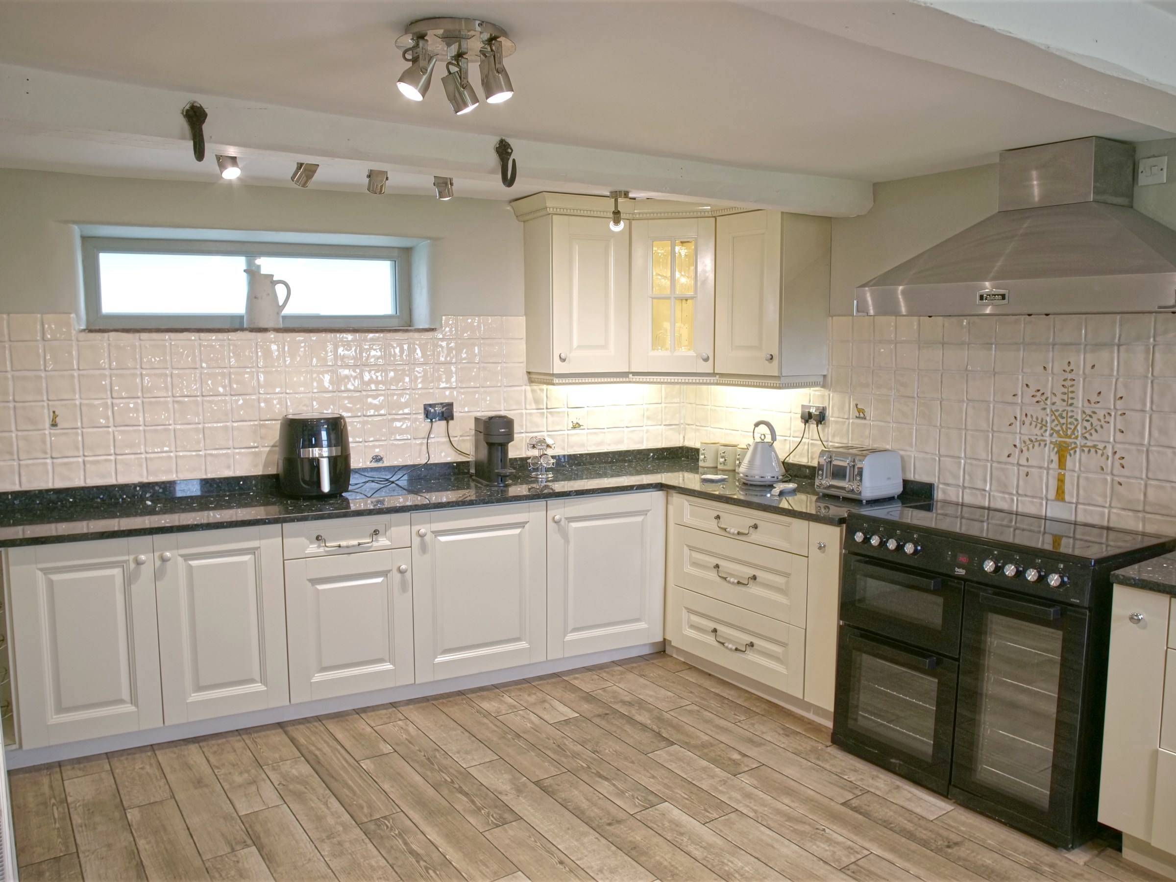 Modern kitchen with beige cabinets, black countertop, and stainless steel appliances.