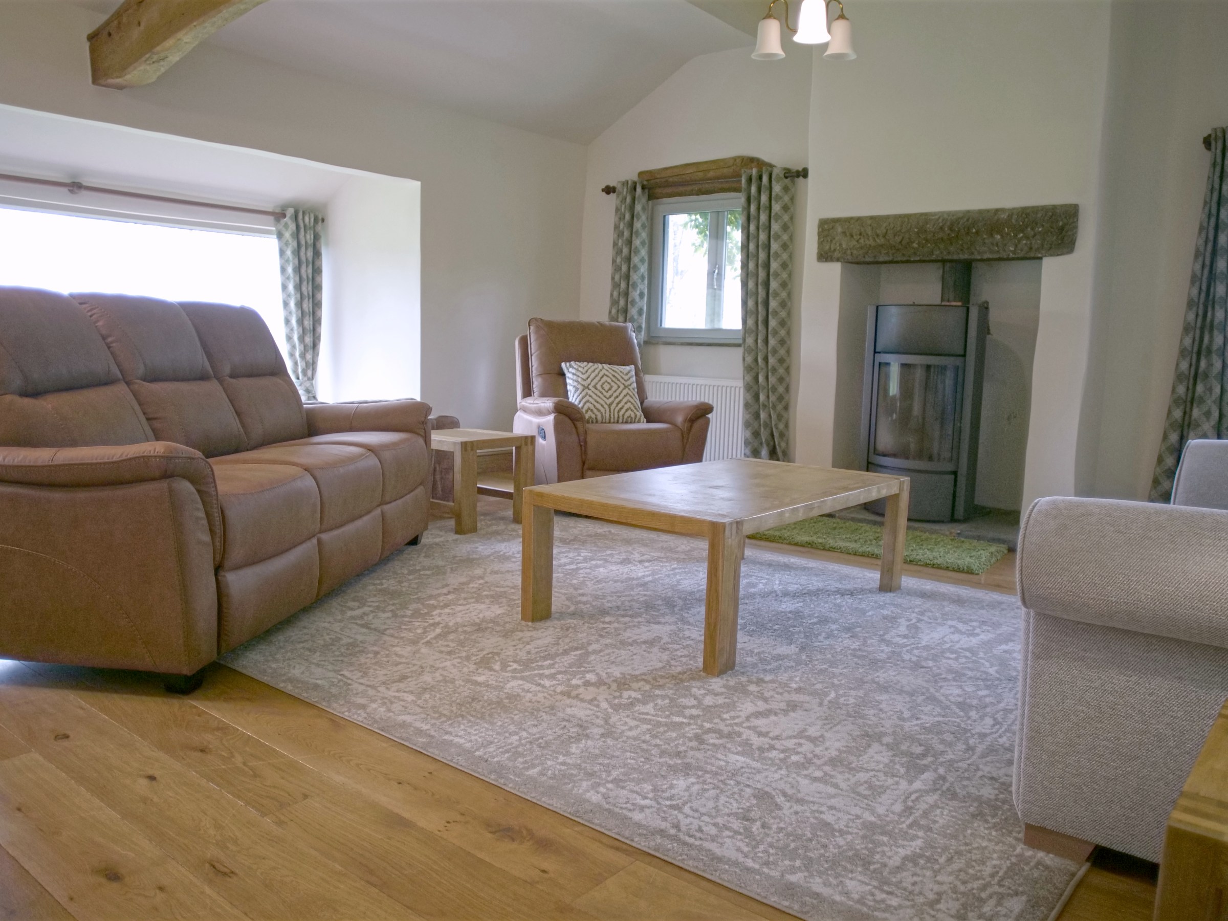 Living room with leather sofa, armchair, coffee table, and large window view.