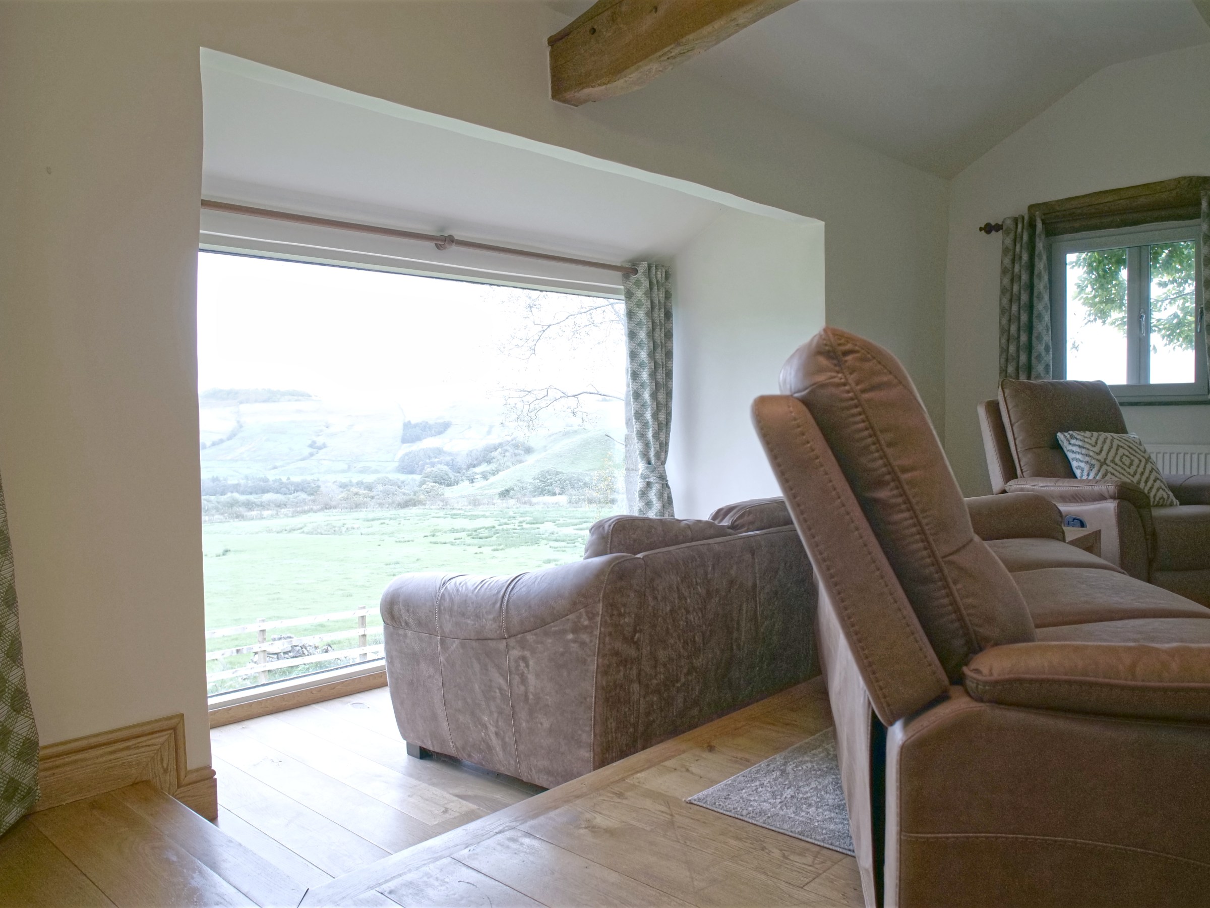 Cozy room with large window, brown armchairs, and scenic countryside view.